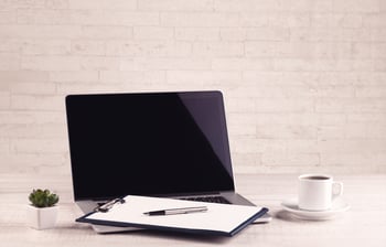 Close up of business office desk with pen board coffee in front of empty white brick textured wall background.