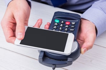 Man using smartphone to express pay on a wooden table